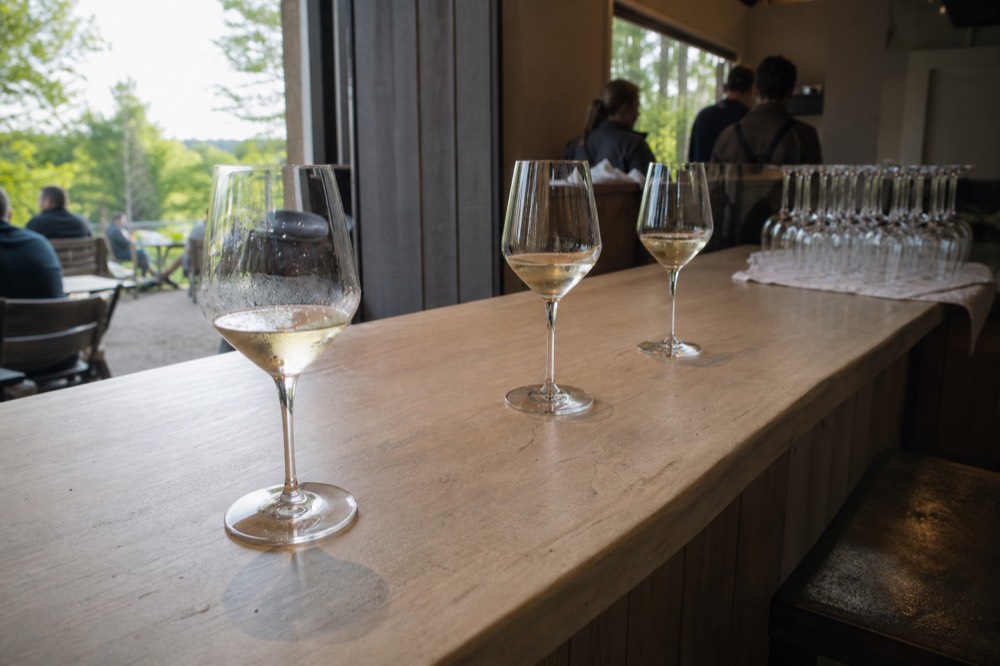 A flight of white wine glasses lined up on a wooden tasting bar, no text, no logos, no people