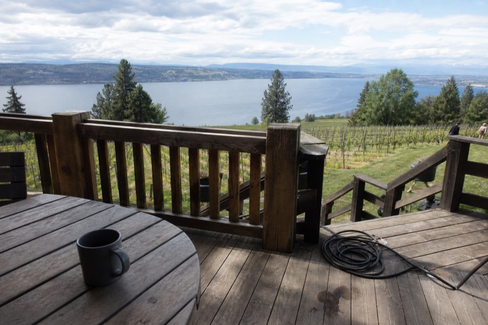 Wooden tasting room deck overlooking vineyard rows and a long glacial lake, no text, no logos, no people