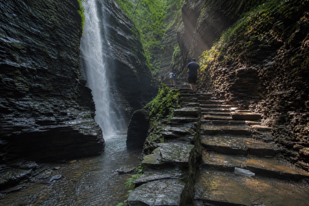 A waterfall dropping through a rock gorge with stone steps, no text, no logos, no people