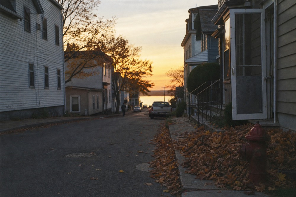 A quiet village street with lake water visible between buildings, no text, no logos, no people