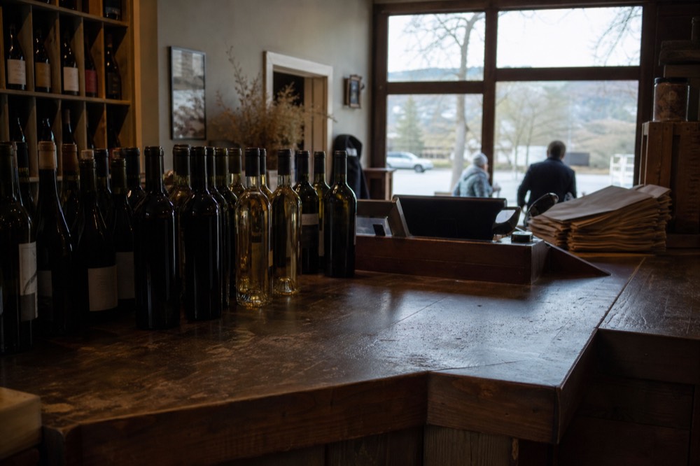 A cashier counter with wine bottles for sale in a tasting room, no text, no logos, no people