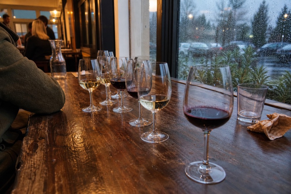 A tasting room bar with glasses of white and red wine lined up on a wooden counter, no text, no logos, no people