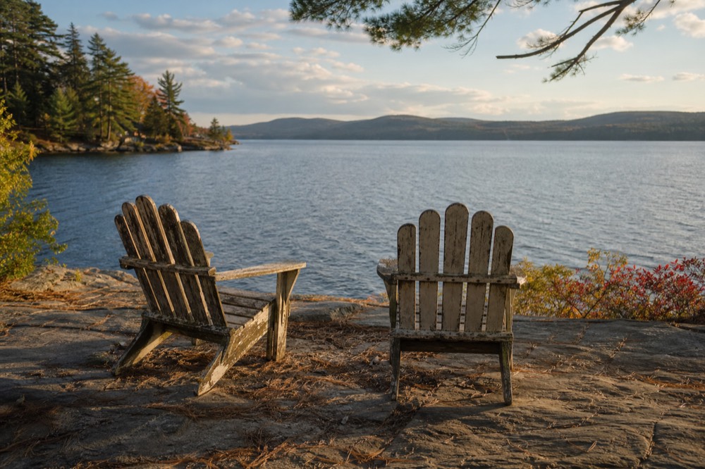 A quiet lakeside overlook with Adirondack chairs in late afternoon light, no text, no logos, no people