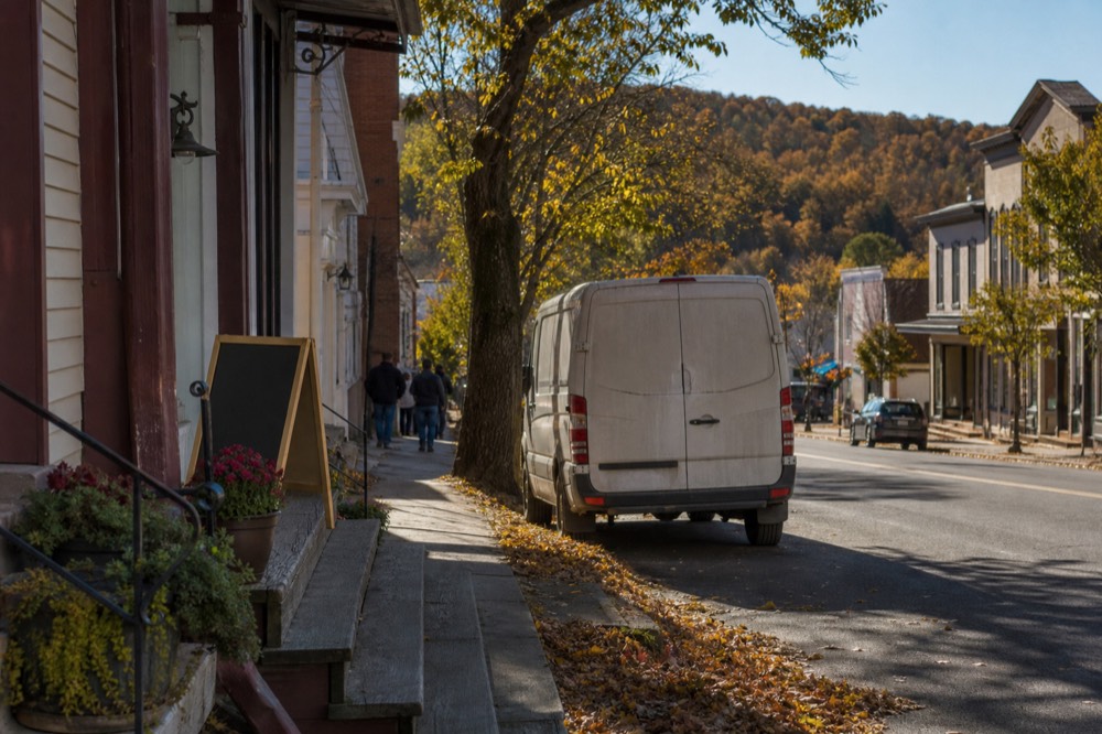 A small-town main street in the Finger Lakes with storefronts and hills beyond, no text, no logos, no people
